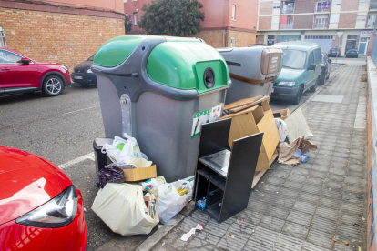 Dos contenedores de Lleida ciudad rodeados de varias bolsas de basura y mobiliario en mal estado. 