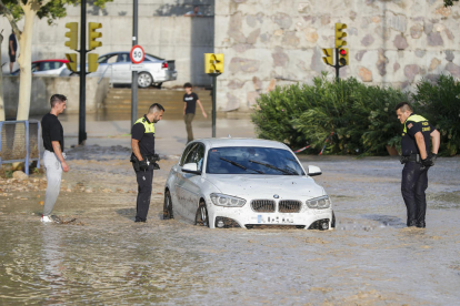 AgAgentes de la Policia Local observen un cotxe arrossegat per la tempesta caiguda aquest dijous en Zaragoza.entes de la Policia Local observen un cotxe arrossegat per la tempesta caiguda aquest dijous a Saragossa.