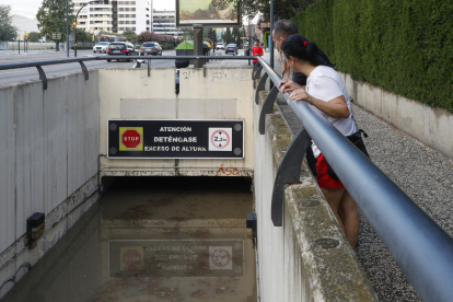 Dos personas observan el nivel alcanzado por el agua, de casi dos metros de altura, en un paso subterráneo en Zaragoza