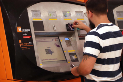 Un chico utilizando una máquina de autoventa de Rodalies el primer día en vigor de los abonos gratuitos.