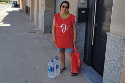 Vecinos de Bovera hacían cola el viernes para llenar sus garrafas ante una cuba con un eslógan a favor de beber agua del grifo.