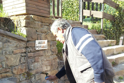 Vecinos de Bovera hacían cola el viernes para llenar sus garrafas ante una cuba con un eslógan a favor de beber agua del grifo.