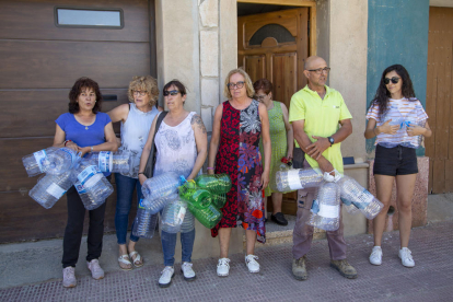 Vecinos de Bovera hacían cola el viernes para llenar sus garrafas ante una cuba con un eslógan a favor de beber agua del grifo.