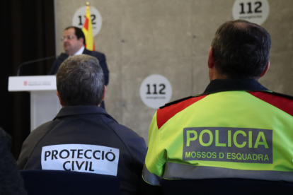Dos agents de Protecció Civil i dels Mossos d'Esquadra en la roda de premsa d'aquest dimecres sobre les novetats del PLASEQTA, amb el conseller d'Interior, Joan Ignasi Elena, al fons