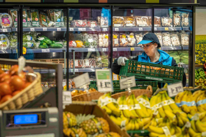 Una trabajadora reponiendo fruta en un supermercado.