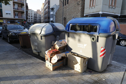 Cajas al lado de un contenedor de papel y cartón en la plaza Santa Maria Magdalena (Clot).