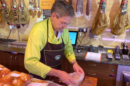 Un carnisser de la Seu d'Urgell, introduint part de la compra d'un client en una carmanyola.