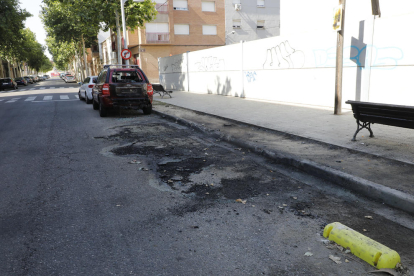 Restes de contenidors cremats, amb un vehicle afectat, diumenge a la Bordeta.