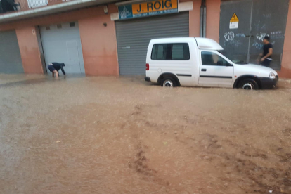 Una de las calles inundadas ayer en Torà, y, a la derecha, pasajeros del tren de La Pobla subiendo al autocar en la estación de Balaguer. 