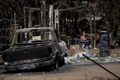 Una dona camina entre les ruïnes d’una casa destruïda per l’incendi a la localitat de Lahaina.