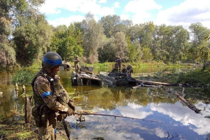 Tropas ucranianas pescan e inspeccionan tanques destruidos.