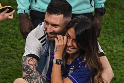 Leo Messi, con la copa del Mundial en el interior del avión de vuelta a Argentina. A la derecha, con su esposa en el césped del estadio.