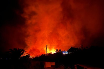 Uns veïns observen com el foc corre turó a baix sense control.