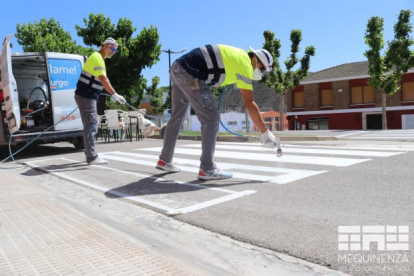 Operaris pintant un dels passos zebra de Mequinensa.