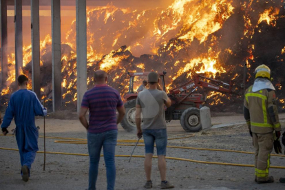 Veïns observant ahir les tasques d'extinció del foc en un paller a la partida Grealó