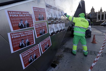 Personal de neteja eliminant pintades i retira cartells contra la cimera a Monjuïc.