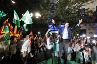 El candidato del PP, Juanma Moreno, saluda a los  a las puertas de la sede del partido en Sevilla