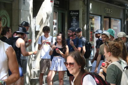 Un grup de joves menja un gelat per refrescar-se a la Rambla de Girona