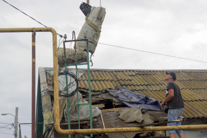 Treballadors extreuen una part d’un coet del sostre d’un edifici atacat a Odessa.