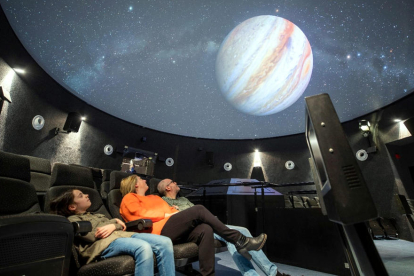 Tres visitants gaudeixen de la projecció d'una pel·lícula al planetari del Parc Astronòmic del Montsec (PAM) d'Àger.