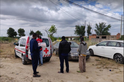 Voluntarios de la Cruz Roja atendiendo usuarios de un asentamiento de temporeros