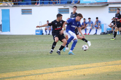 El atacante del Mollerussa Adri Fernández protege la posesión, con Toni Vicente intentando ganarle la posición para robar el balón. 