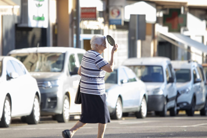 Una dona es protegeix del sol mentre travessa el carrer a Lleida.