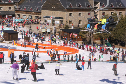 El rei Felip VI esquiant ahir a Baqueira (esquerra) i un gran nombre d’esquiadors a l’estació de Port Ainé, que va tancar l’accés al completar l’aforament.