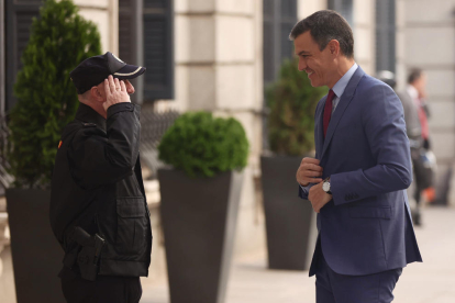 Un policía saludando ayer a Pedro Sánchez a su llegada al Congreso para la sesión de control.