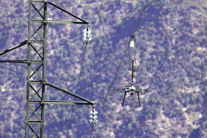 Un dron instalando uno de los elementos catadióptricos sobre la línea, en el municipio de Rialp, en el Pallars Sobirà.