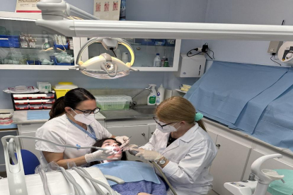 Dos higienistas dentales atienden a una paciente.