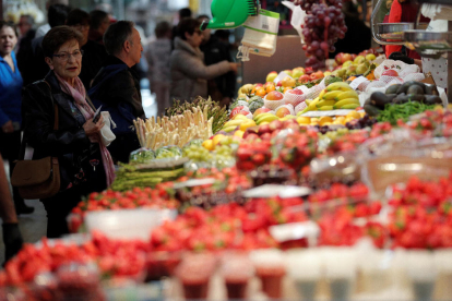 Una mujer comprando frutas y verduras en un mercado.