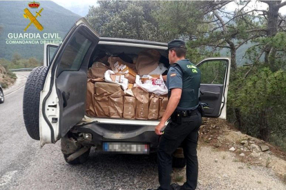 Un agente de la Guardia Civil muestra el maletero de un todoterreno donde han encontrado más de 5.300 paquetes de tabaco de contrabando
