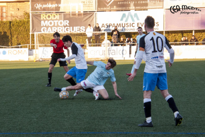 Un jugador del Alguaire se lanza al suelo y se lleva el balón ante la atenta mirada del árbitro.