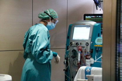 Un malalt és atès per una infermera a l'UCI de Vall d'Hebron.