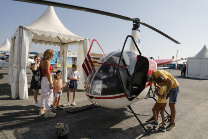 Visitants davant d’un helicòpter en exposició ahir a la fira aeronàutica de l’aeroport d’Alguaire.