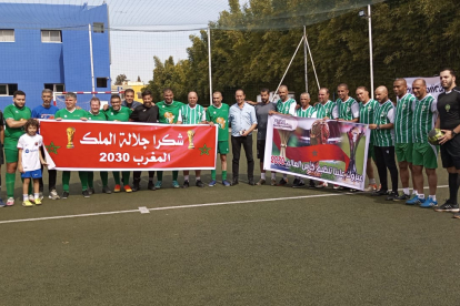 L’equip de Lleida i el de veterans del KAC de Kenitra posen abans d’un partit amb la pancarta recordant el Mundial 2030.