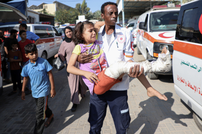 Un sanitari trasllada una nena ferida al pas de Rafah.