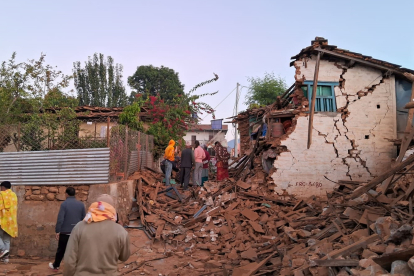 Supervivents del terratrèmol davant d’una casa esfondrada al Nepal.