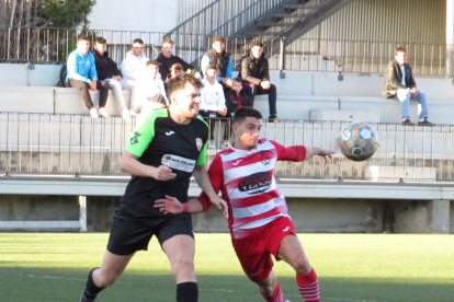 Un futbolista de l’Almacelles forceja amb un rival per intentar emportar-se la pilota.