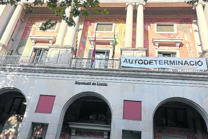 La façana de la Diputació sense la pancarta i, a la imatge de la dreta, dos persones aguantant el cartell que van arrancar.