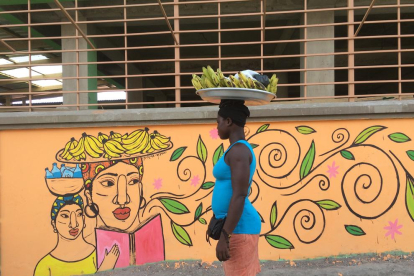 akkra. A la dreta, una dona observant una pintura de les dones africanes que va fer la Cristina a Akkra. A baix, un dels seus murals.