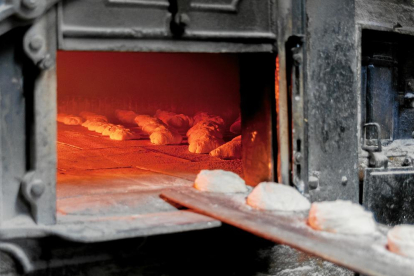 Uns quants pans de ronyó es couen al forn de pedra mentre n'introdueixen de nous amb una pala.