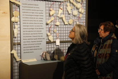 Dos visitants observen els exvots de cera exposats al Museu de Lleida.