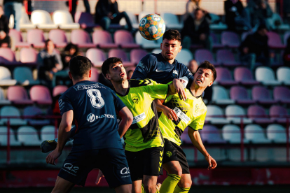 Àngel i Bayu, de l’Atlètic Lleida, pugnen per una pilota amb dos rivals.