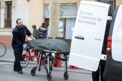Els serveis funeraris retiren el cos sense vida de la dona assassinada pel seu fill a Barcelona.