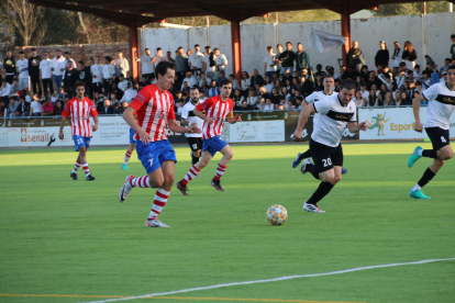 Un jugador del Pobla condueix la pilota vigilat per un rival que segueix l’acció.