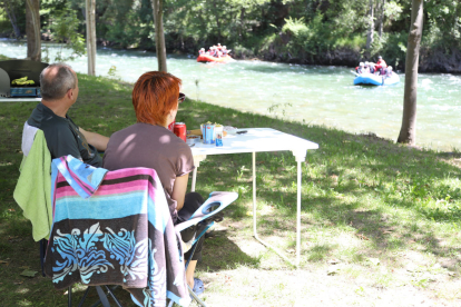 Una parella d’acampada en un establiment del Sobirà mira les barques fent ràfting a la Noguera Pallaresa.