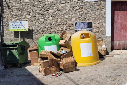 Imatge d’alguns contenidors buits mentre els residus de cartró s’acumulen al carrer.