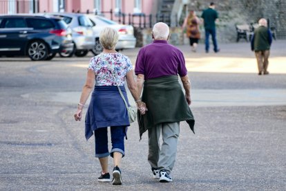 Una pareja de jubilados pasea por la calle.